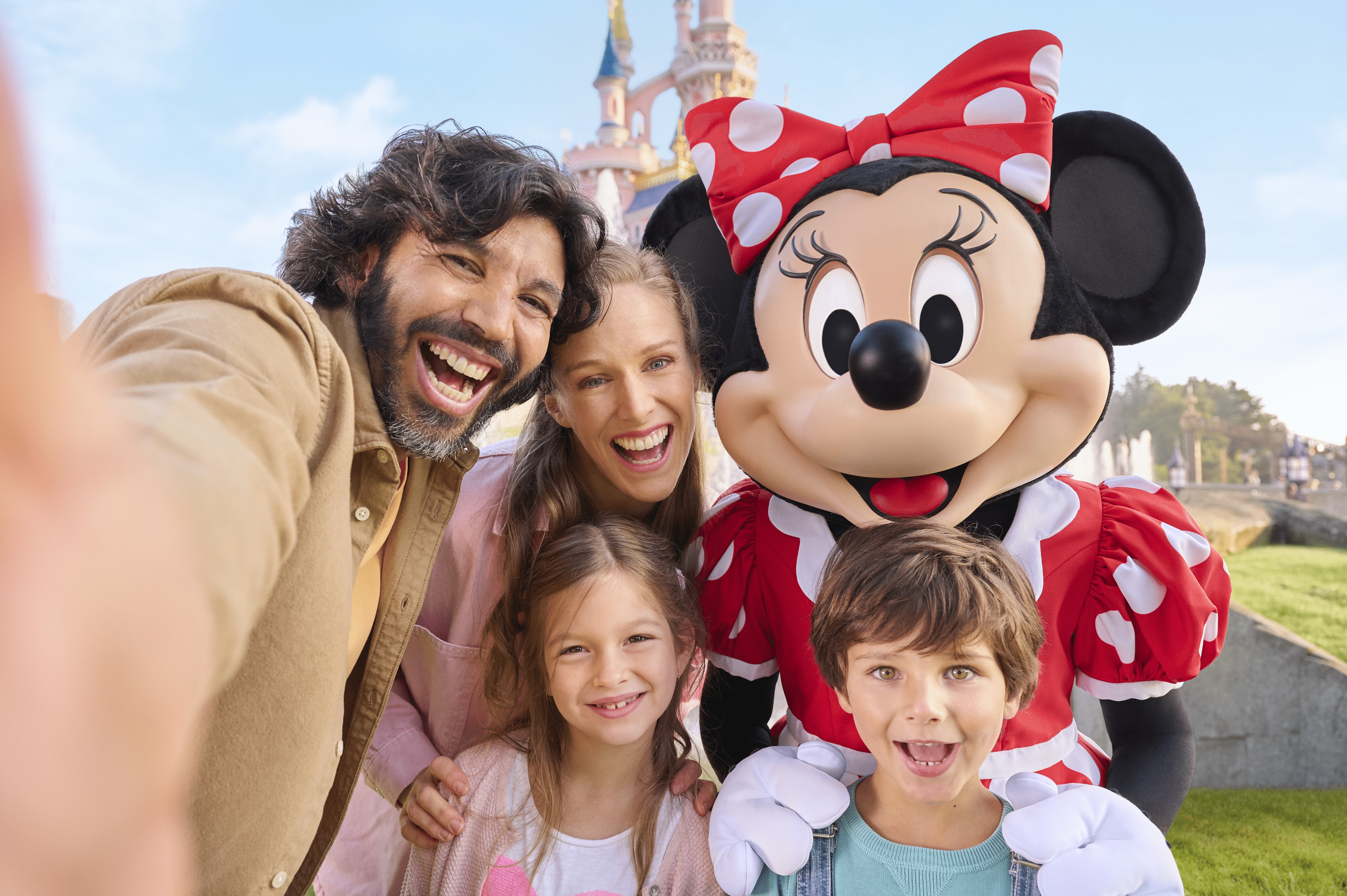 A family taking a selfie with Minnie Mouse in front of the castle at Disneyland Paris